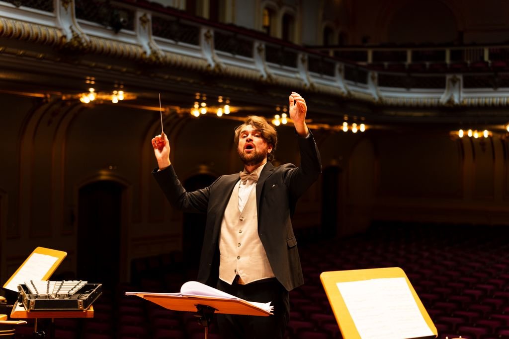 Orchestra conductor passionately leading a performance in an elegant concert hall. – chef d'orchestre