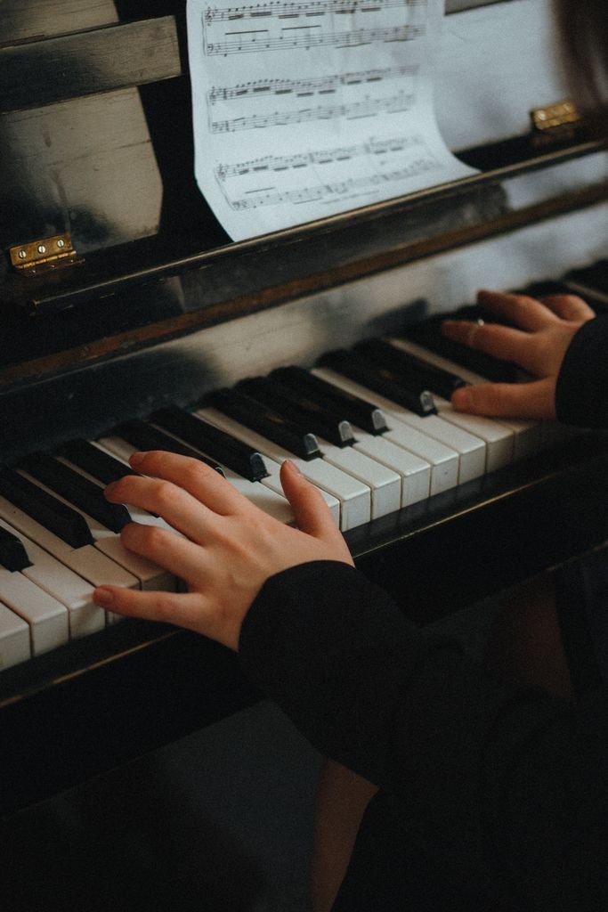 Hands playing piano with music sheet in view. Intimate and artistic setting. – le lied
