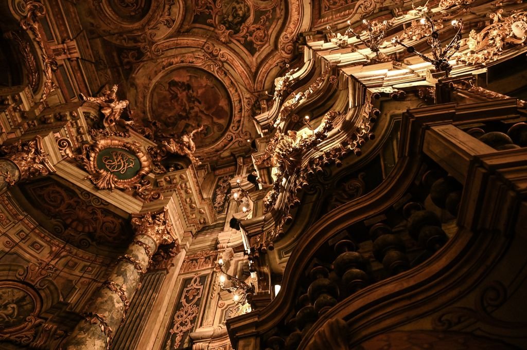 Intricate baroque interior with detailed carvings and golden ornamentation, showcasing architectural elegance.
