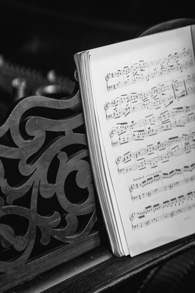 Opened music book with white pages and black notes placed on wooden piano in light room
